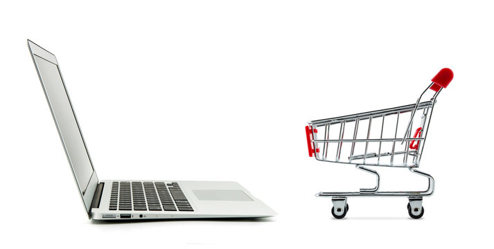 Shopping cart and laptop computer isolated on white background, shop online concept.