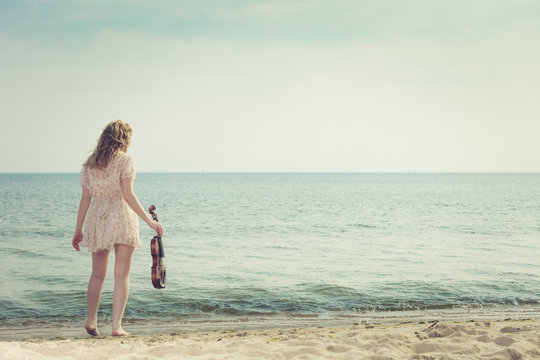 Woman on beach near sea holding violin