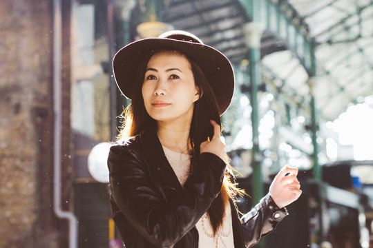 Asian lady in the rain wearing a floppy hat adjusting her hair at Borough Market, London
