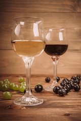 Red and white wine glasses and grape on wooden table