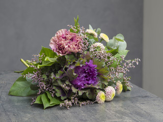 bouquet of flowers pink violet and green with decorative cabbage on grey background