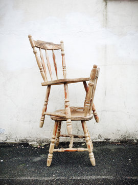 Two wooden chairs stacked by a wall