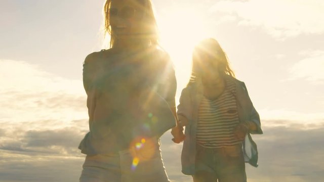Two Beautiful Girls Holding Hands and Running into the Cloudless Happy Future. Clear Sky in the Background. Shot on RED EPIC-W 8K Helium Cinema Camera.