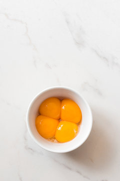 egg yolks in a ramekin bowl on a marble background