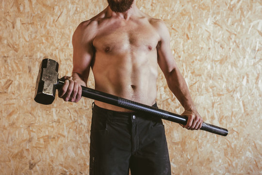 Man holding a heavy hammer to hit a tire.