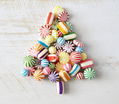 Colorful, hard, candy pieces arranged in tree shape on white surface