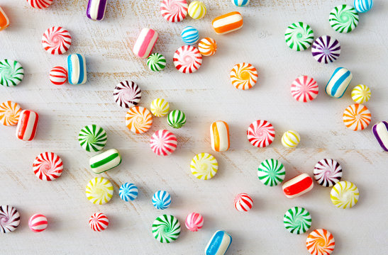 Colorful, hard, candy pieces scattered on white surface