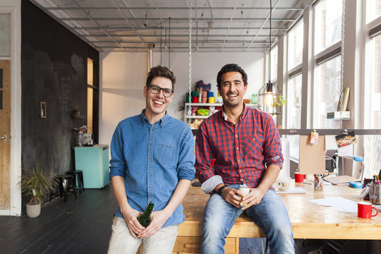 A team of two entrepreneurs or professionals sitting on their desk and having a beer