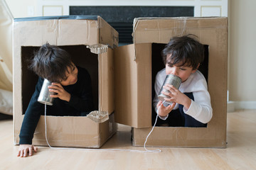talking and listening over a tin can telephone, two children