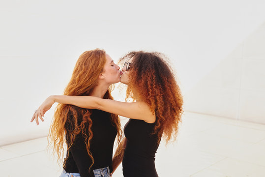 Two young women kissing against of white background