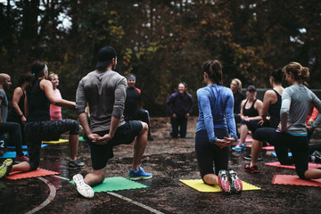 Fit people stretching arms and back outside in group workout