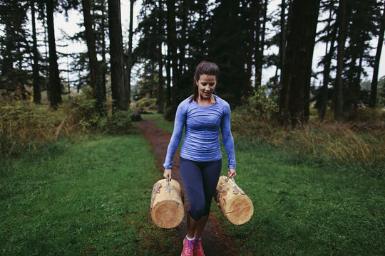 Woman Walking With Heavy Logs At Rainy Outdoor Bootcamp