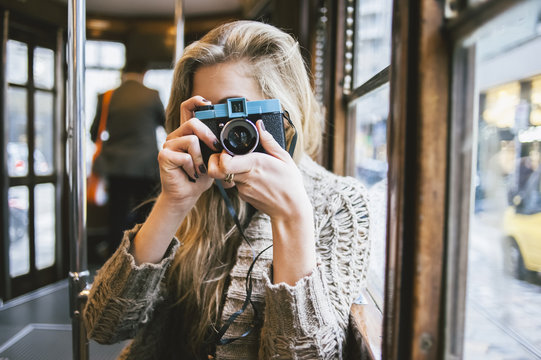 Young woman using a film camera on the tram