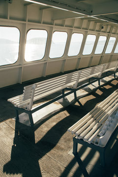Windows and benches illuminated by sunlight on upper deck of passenger ferry