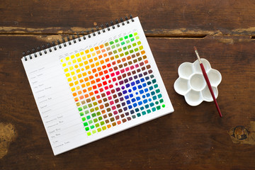 A sketchbook, palette, and paintbrush on a table