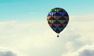 Aerostat floating in day sky. Mixed media