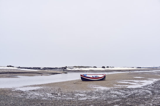 Boats and snow at low tide. Burnham Overy Staithe, Norfolk, UK.