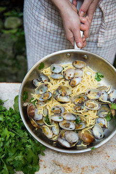 Girl holding a pan full of spaghetti vongole with clams
