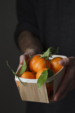 Man holding a basket of mandarin oranges