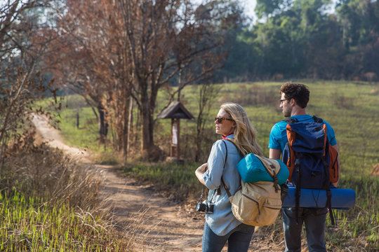 Couple walking with backpacks outdoors - adventure, travel, tourism