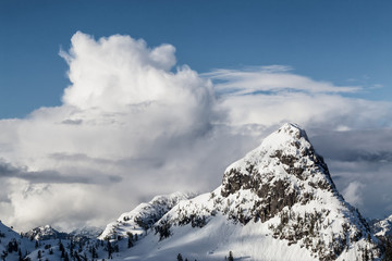 Aerial landscape view of the snow and cloud covered mountain range North of Vancouver, British Columbia, Canada.