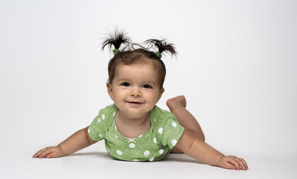 Adorable Baby Girl In Green Polka Dot Onesie Lying On Stomach