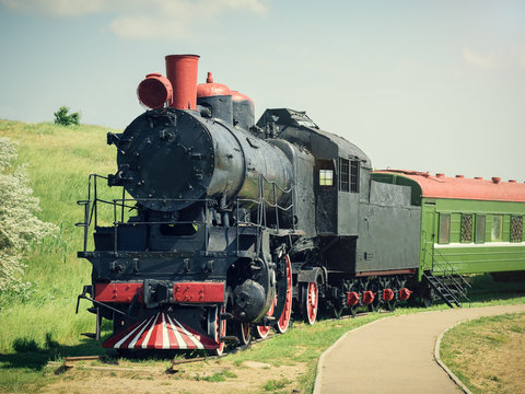 Fototapeta Classic vintage train with a green car on the tracks in summer day.