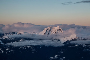 Fototapeta na wymiar Aerial Landscape View of Garibaldi Mountain covered in Clouds during a colorful Sunset. Picture taken in Squamish, British Columbia, Canada.