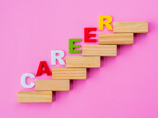 Wood block stacking as step stair with colorful of "CAREER" word on it in pink background. Business concept for success process.