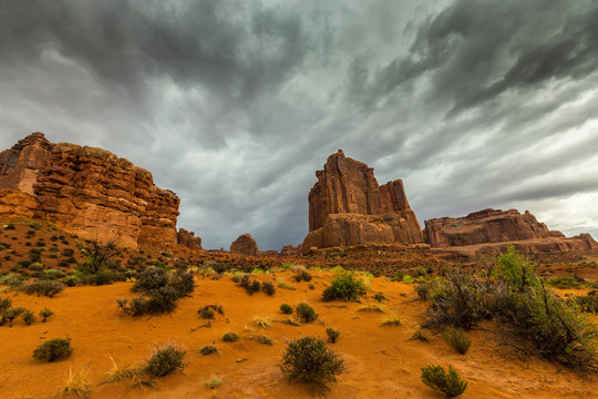 Dramatic storm clouds, rain, and red sandstone formations in the Arches National Park, Utah