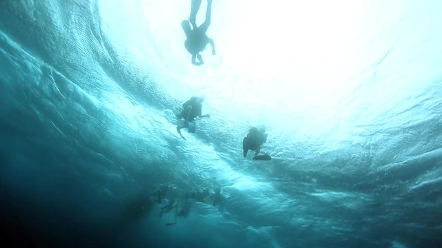 Scuba divers silhouettes on rough ocean surface at end of dive 