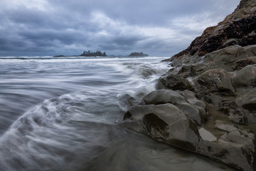 View on the Pacific Ocean Coast during a cloudy winter sunset. Picture taken in Chesterman Beach, Tofino, BC, Canada.