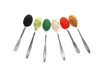 Different colorful superfood powders in spoons on white background