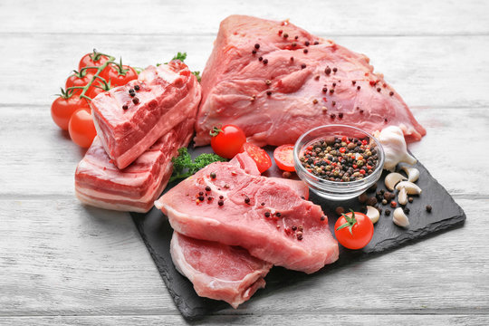 Slate plate with different types of meat on wooden table