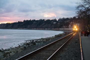 White Rock, British Columbia, Canada - April 01, 2017 - A freight train riding through the city by the beach during a colorful spring sunset. © edb3_16