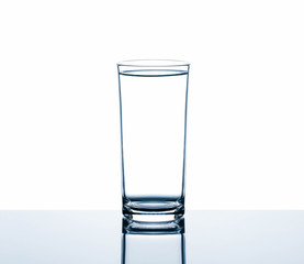 Drinking water in glass on reflection glass table isolated on white background