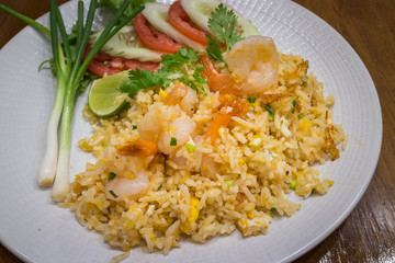 Healthy prawn or shrimp fried rice in a white dish on wood table background for ready to serve.