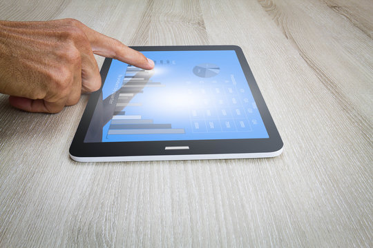 Man's hand using tablet computer on wooden desk, business technology concept
