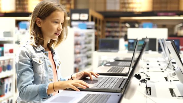 Young girl in multimedia store looking at laptop
