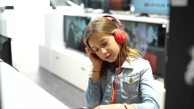 Young girl in multimedia store listening to music
