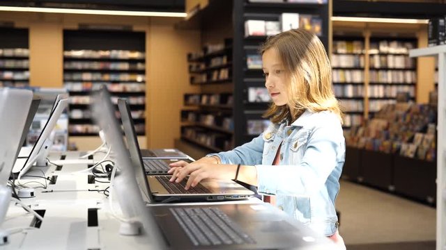 Young girl in multimedia store looking at laptop