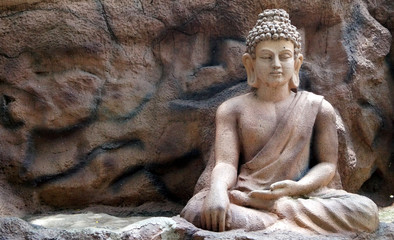 Statue of Buddhist God Buddha in sitting and meditating pose in a park 