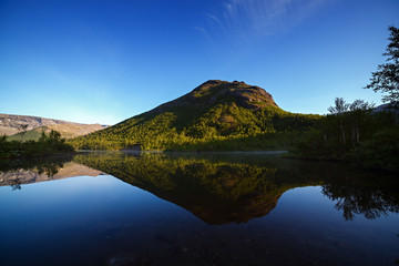 Mountains reflected in the smooth surface of the lake at dawn.