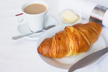 Fresh french croissant served with, butter and a cup of coffee with milk