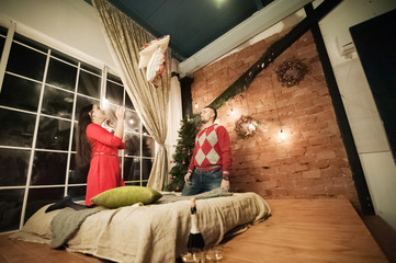 Christmas wall decor in a room in Loft style. A loving couple celebrates Christmas together. Lovers throw cushions in the bedroom in the Loft style.