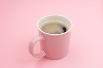 Pink mug with coffee on pink background