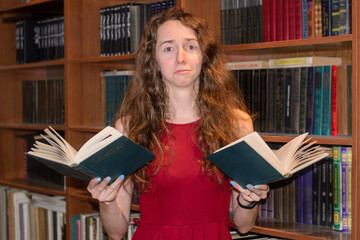 Young student girl does not want to learn.  She holds two books in her hands and and has a sad look