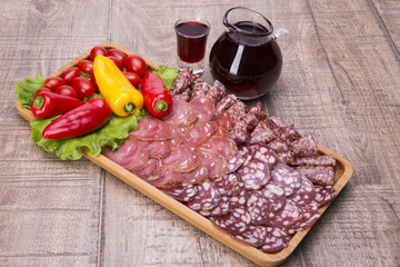 Set of meat delicatessen, tomatoes and peppers,.  wine on a wooden table.