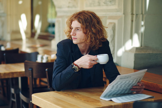 Young reddish man drinking coffee while looking to right