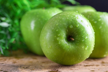 Ripe green apples with water dropletson wooden background